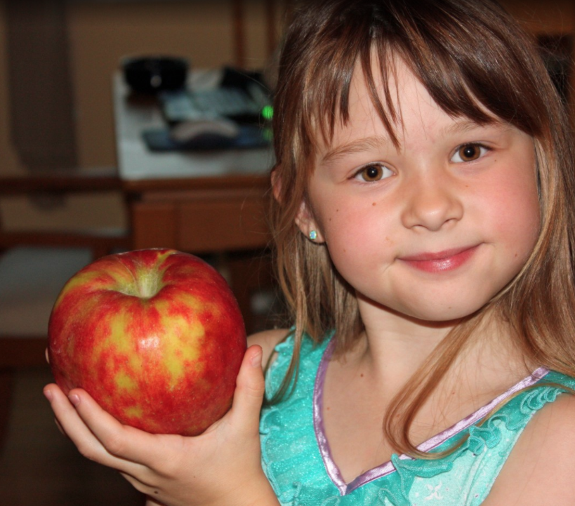 young girl holding an apple